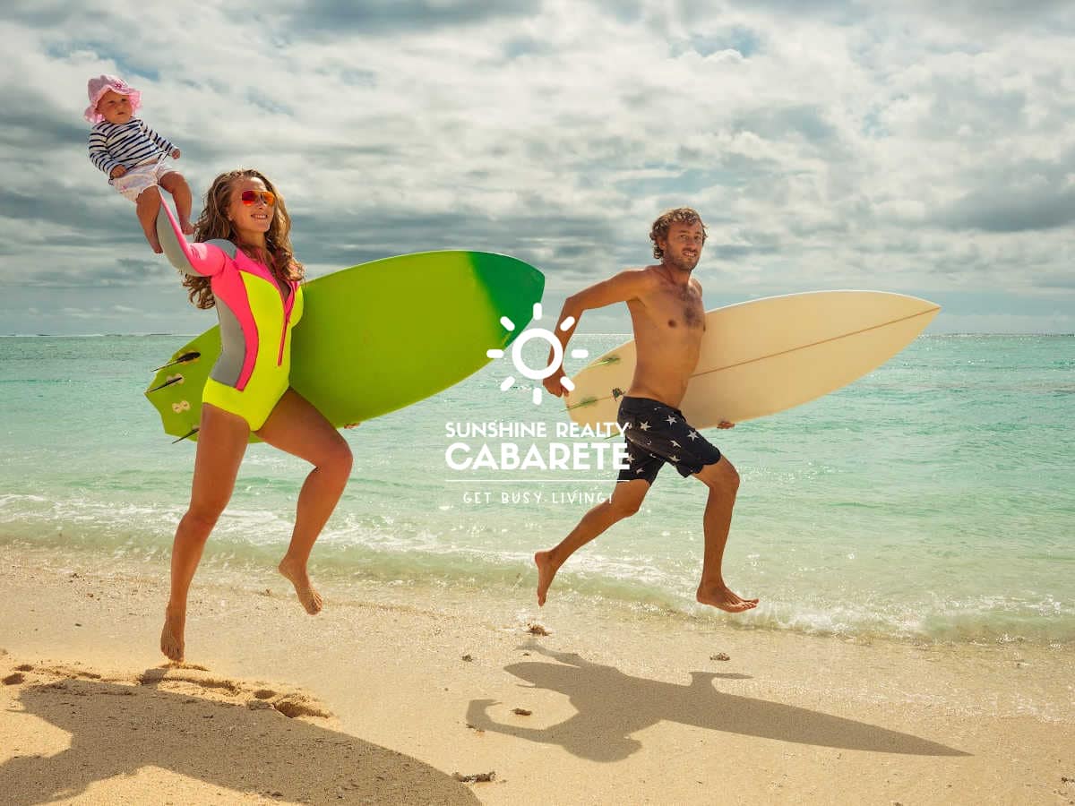 Image of a young family running down the beach with surfboards in Cabarete, Dominican Republic